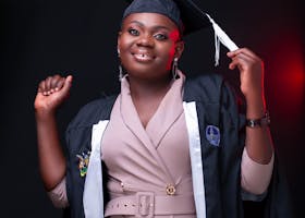 A joyful graduate poses confidently in her cap and gown, celebrating her achievement.