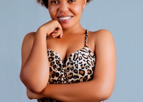 Woman smiling confidently in a leopard print dress against a neutral background.