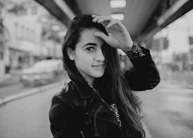 Black and white portrait of a woman in a leather jacket on an urban street.